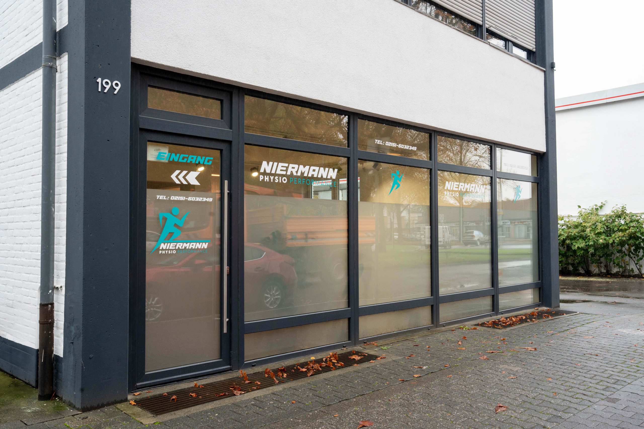 Fassade des Gebäudes mit dem Eingang und dem Schriftzug Niermann Phyiso Performance auf den Fenstern.