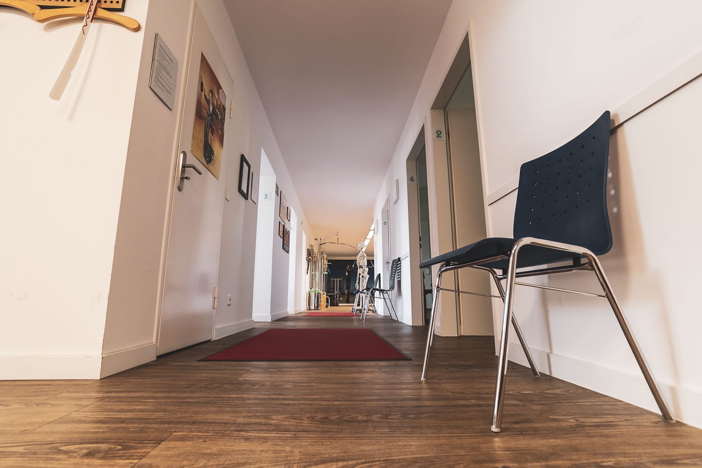 Flur in einer Physiotherapiepraxis mit Stühlen und mehreren Türen zu Behandlungsräumen.
