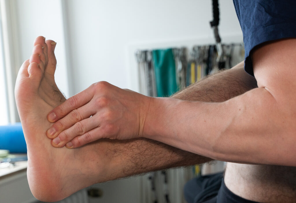Physiotherapeut dehnt den Fuß eines Patienten.